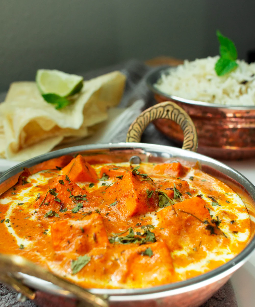Creamy paneer butter masala garnished with fresh cream, served with rice and papad
