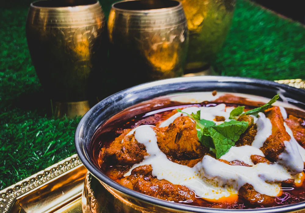 Butter chicken in a copper handi, freshly prepared in the NIOM FOODS cloud kitchen